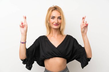 Parmakları geçiş ve en iyi dilek ile izole beyaz duvar üzerinde Genç sarışın kadın