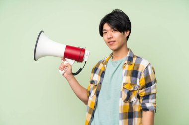 Bir megafon tutan izole yeşil duvar üzerinde Asyalı adam