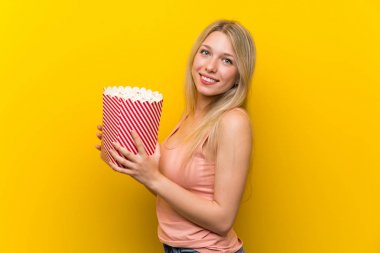 Pembe duvar üzerinde patlamış mısır ile genç kadın