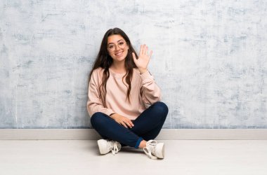 Genç öğrenci kız mutlu ifade ile el ile selamlama bir masada okuyan