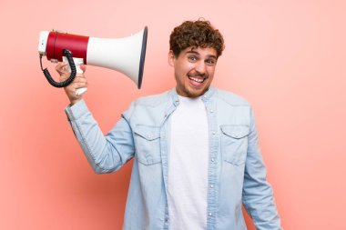 Sarışın adam pembe duvar üzerinde çok gürültü yapan bir megafon alarak