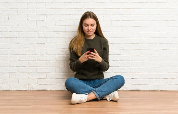 Junge Frau Sitzt Auf Dem Boden Und Sendet Eine Nachricht — Stockfoto