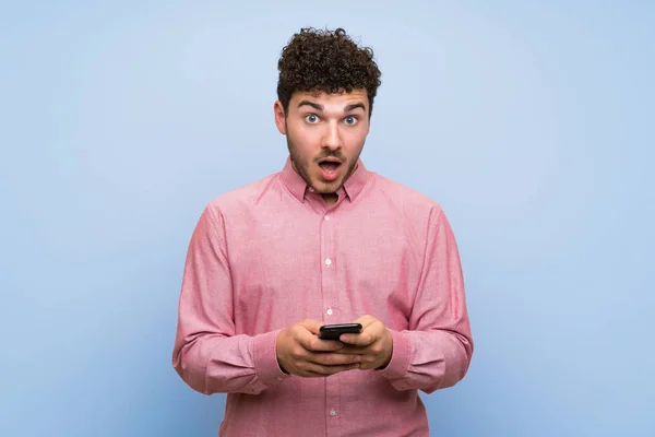 Hombre Con Pelo Rizado Sobre Pared Azul Aislado Sorprendido Enviando —  Fotos de Stock