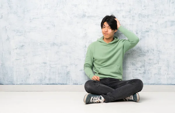 欲求不満の表情と理解していない床に座っているアジア人男性 — ストック写真