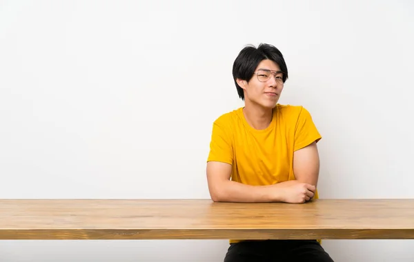 Asian man with yellow shirt with glasses and smiling