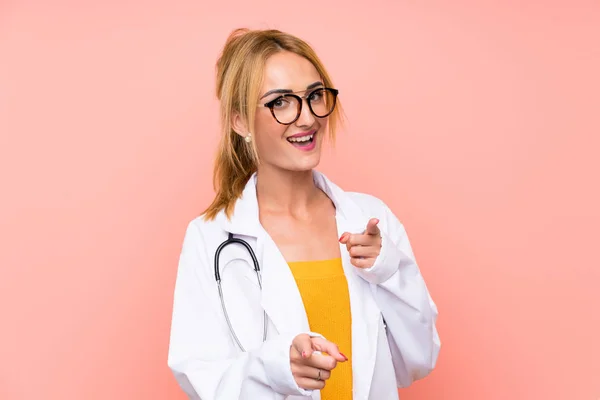 Young blonde doctor woman points finger at you