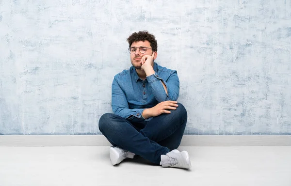 Gözlükle yerde oturan genç adam