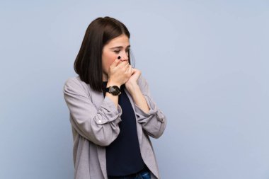 Ağız kapsayan izole mavi duvar üzerinde genç kadın ve yan bakıyor