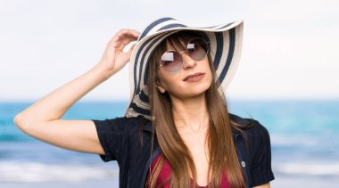 Bikinili genç bir kadının şüpheleri var ve plajda kafası karışmış bir yüz ifadesi var.