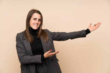 Young woman over isolated wall extending hands to the side for inviting to come
