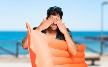 Plajda elleri ile gözleri kaplayan şort adam