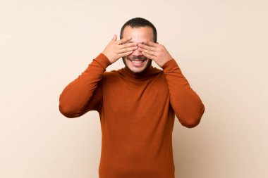 Boğazlı kazak ile Kolombiyalı adam elleri ile gözleri kapsayan