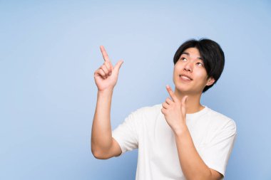 Işaret parmağı ile işaret izole mavi arka plan asyalı adam harika bir fikir