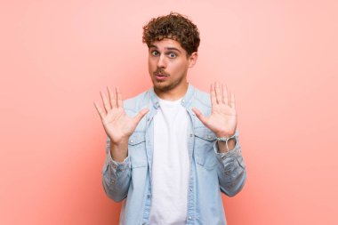 Pembe duvar üzerinde Sarışın adam iki eliyle stop jest yapma