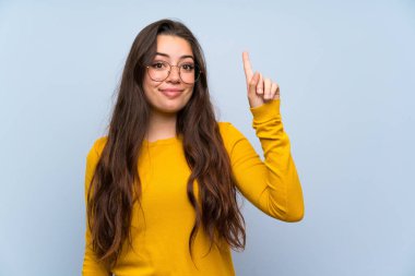 İşaret parmağı ile işaret izole mavi duvar üzerinde Genç kız harika bir fikir