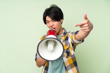 Bir megafon ile bağırarak izole yeşil duvar üzerinde Asyalı adam