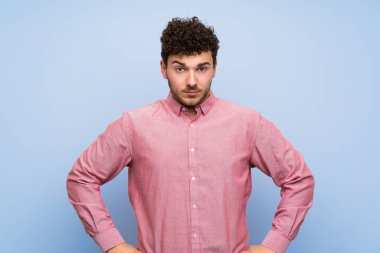 Izole mavi duvar kızgın üzerinde kıvırcık saçlı adam