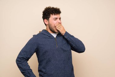 İzole duvar esneme üzerinde kıvırcık saçlı adam esneme ve el ile geniş açık ağız kapsayan