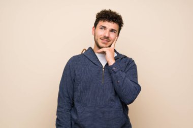 İzole duvar üzerinde kıvırcık saçlı adam yukarı bakarken bir fikir düşünme