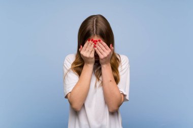 Yorgun ve hasta ifade ile mavi duvarın üzerinden genç kadın