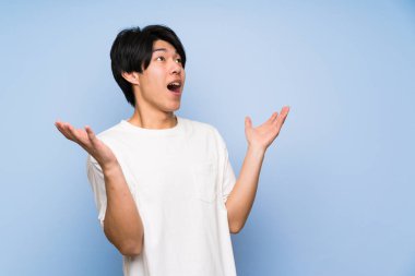 Sürpriz yüz ifadesi ile izole mavi arka plan Asyalı adam