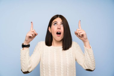 İşaret parmağı ile işaret izole mavi duvar üzerinde genç kadın harika bir fikir