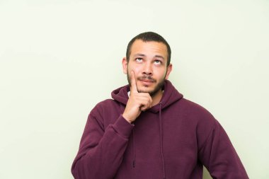 Yeşil duvar üzerinde sweatshirt ile Kolombiyalı adam bir fikir düşünme
