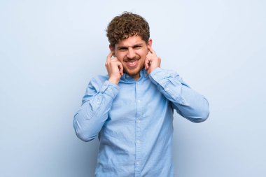 Mavi duvar sinirli ve kaplama kulakları sarışın adam