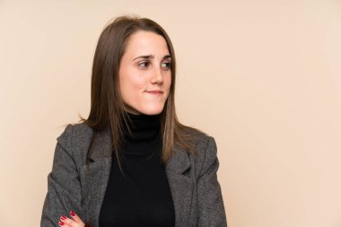 İzole edilmiş duvarın üzerinde duran ve yana bakan genç bir kadın.