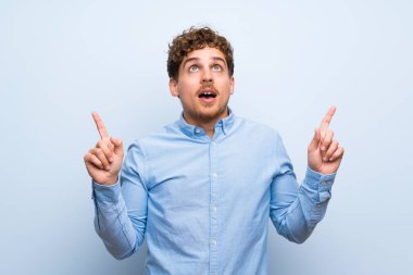 Sarışın adam şaşırttı ve yukarı dönük mavi duvarın üzerinden