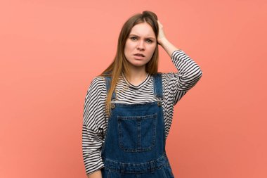 Pembe duvarın üstünde sinirli ve anlamayan genç bir kadın.