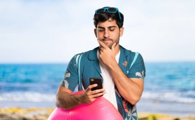 Şortlu adam sahilde bir mesaj düşünüyor ve gönderiyor