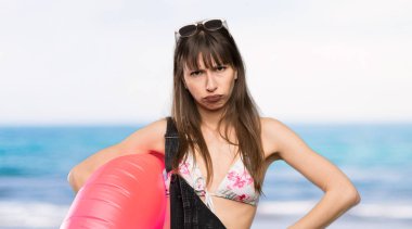 Kumsalda kızgın bikinili genç bir kadın.