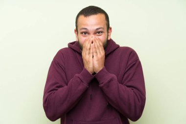 Sürpriz yüz ifadesi ile yeşil duvara Sweatshirt ile Kolombiyalı adam