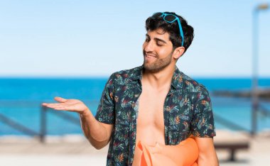 Plaja doğru gülümseyerek bakarken şortlu adam bir fikir sunuyor