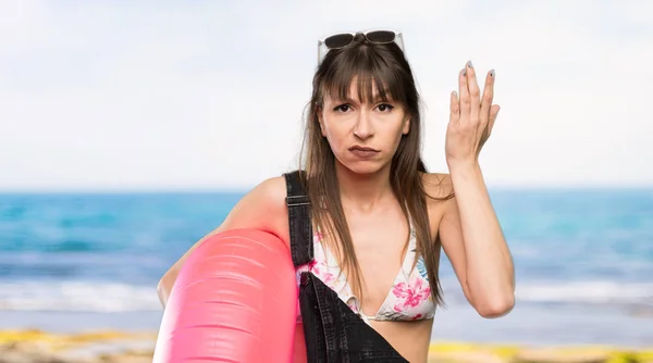 穿着比基尼的年轻女人做了个疯狂的动作 把手指放在海滩的头上 — 图库照片
