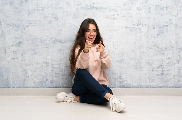 Genç öğrenci kız ön işaret eden bir masada okuyan ve gülümseyen