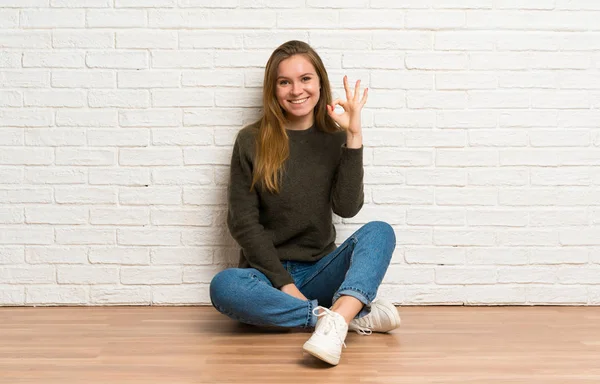 Jovem Mulher Sentada Chão Mostrando Sinal Com Dedos — Fotografia de Stock