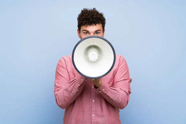 Man Met Krullend Haar Geïsoleerde Blauwe Muur Schreeuwen Door Een — Stockfoto