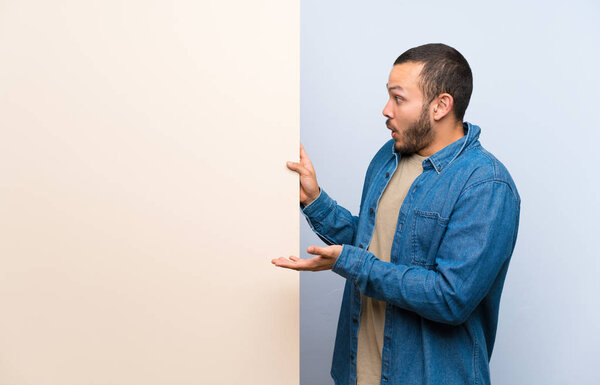 Colombian man holding an empty placard holding copyspace imaginary on the palm