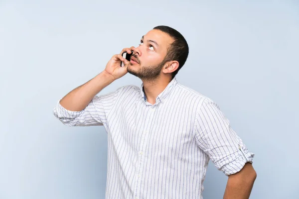 Kolumbijski Człowiek Białym Tle Niebieską Ścianę Prowadzenie Rozmowy Telefonem Komórkowym — Zdjęcie stockowe