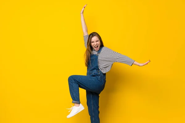 Młoda dziewczyna z kombinezonu skoki na białym tle żółty — Zdjęcie stockowe