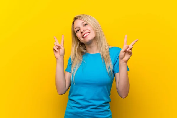 Молода Блондинка Над Ізольованим Жовтим Тлом Показує Знак Перемоги Обома — стокове фото