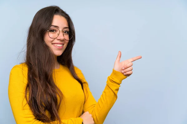 Tiener Meisje Geïsoleerde Blauwe Muur Wijzende Vinger Aan Zijkant — Stockfoto