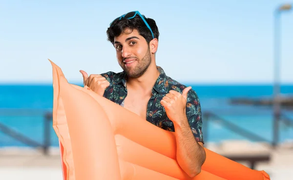 Man in trunks with thumbs up gesture and smiling at the beach