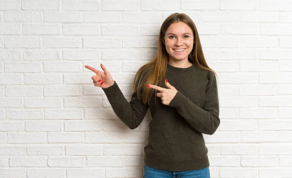 Young Woman White Brick Wall Pointing Finger Side — ストック写真