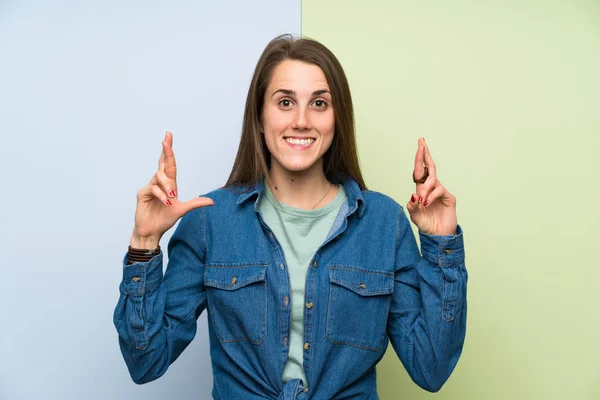 指が交差するカラフルな背景の上に若い女性 — ストック写真