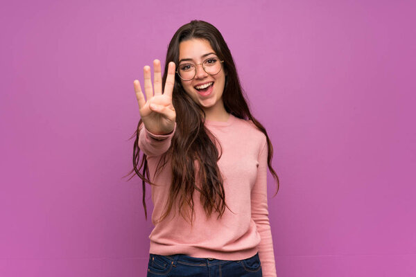 Teenager girl over purple wall happy and counting four with fingers