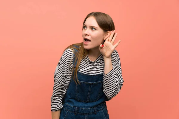 Jonge Vrouw Met Overalls Roze Muur Luisteren Naar Iets Door — Stockfoto