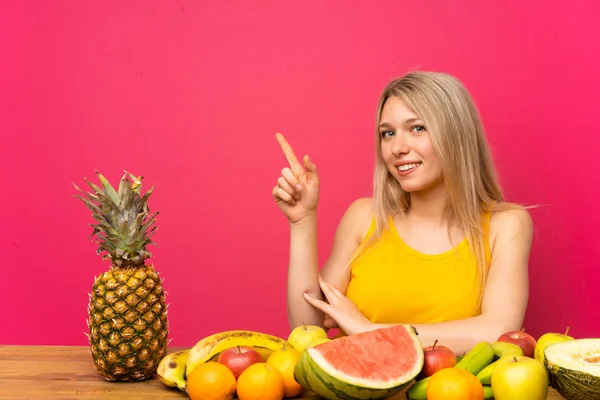 Mujer Rubia Joven Con Muchas Frutas Apuntando Con Dedo Hacia — Foto de Stock